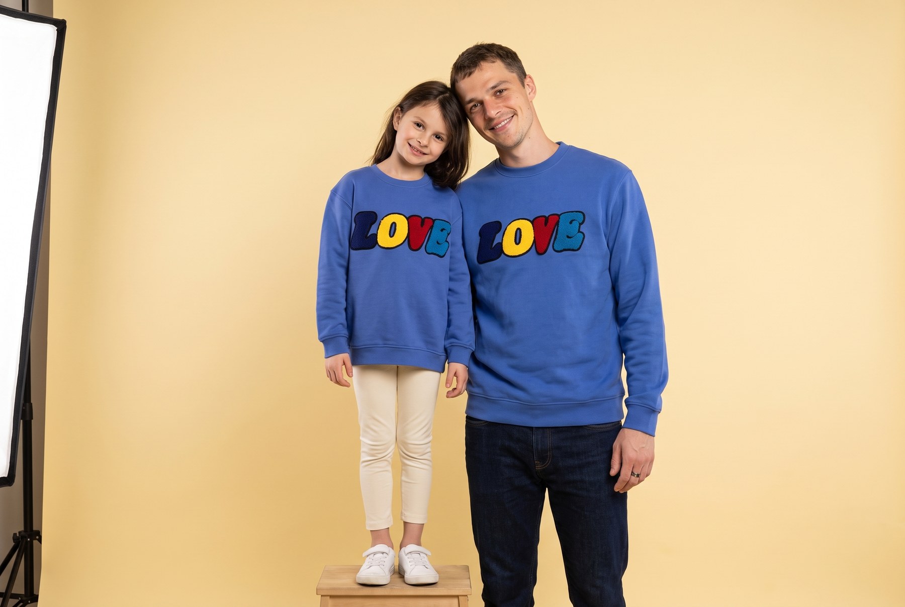 Vater und Tochter im LOVE Sweatshirt Partnerlook vor gelbem Studiohintergrund